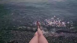 View of sexy female legs on a pebble beach while woman is sunbathing Stock Footage