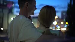 Girl leans on guy shoulder, hugging, looking at night city, closeness, safety Stock Footage
