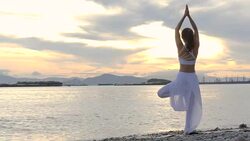 Happy young woman standing yoga pose on the beach at sunset, Sunrise background. Fitness, sport, yoga and healthy lifestyle concept. Stock Footage