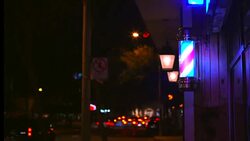 time lapse of a lighted barber pole spinning with nighttime traffic behind Stock Footage