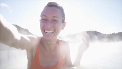 Woman relaxing in hot spring pool in Iceland and takes selfie portrait bathing Stock Footage