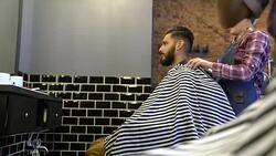 Female barber spreading cape on customer in salon Stock Footage