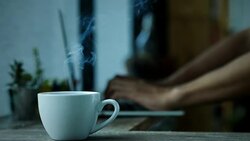 Coffee cup smoke on wood table background man sit and use notebook work in the morning Stock Footage