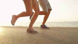 LOW ANGLE: Two training partners running along a scenic coastal road in Slovenia Stock Footage