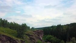 A sniper with a rifle sits on top of the mountain and inspects the territory. View from the drone. the camera moves to the soldier, revealing a view of the landscape Stock Footage