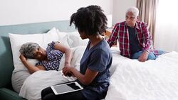 Healthcare worker visiting senior woman suffering with depression lying in bed - shot in slow motion Stock Footage