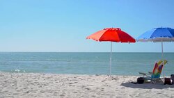 4K Red & Blue beach umbrellas and armchair on the beach Stock Footage