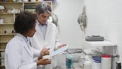 Chemists with tablet PC making pills at pharmacy Stock Footage