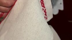 A woman is embroidering an ornament with a red thread. The process of decorating decorative towels embroidered red ornament. Stock Footage