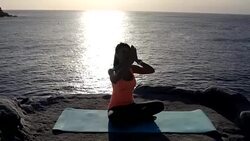 Beautiful young woman practicing lotus position at the top of the cliff near the sea Stock Footage