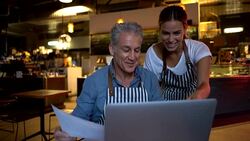 Friendly business owner going over some documents and information of the restaurant with female manager both happy Stock Footage