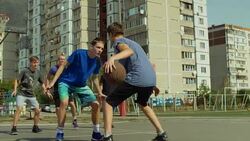 Teenage streetball player dribbling and bouncing the ball on the floor, passing to his teammate while playing basketball game on street. Basketball guard stealing a ball and running in fast break. Stock Footage