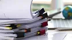 Businessman hands holding pen for working in Stacks of paper files searching information business report papers and piles of unfinished documents achieves on laptop computer desk in modern office Stock Footage