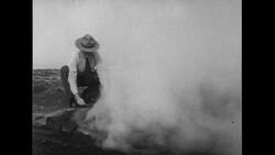 Hawaii, 1952: A man lights a match to create artificial smoke with the help of steam vapors from the earth as lava flows from a volcanic eruption in Hawaii Stock Footage