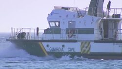 A Close-up leading to a Wide shot of a boat crashing against the waves near Atlanterra Beach News Clip