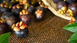 Top view selective focus Fresh delicious harvested mangosteens on wooden table. Thai Tropical Organic purple fruit in the basket. Exotic natural blurred background. Healthy food and eating concept. Stock Footage