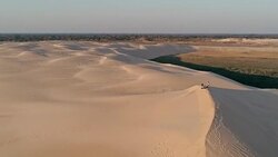 aerial footage of young people standing on the peak of a sand dune in beautiful desert environment Stock Footage