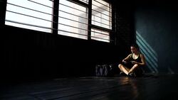 Panning young beautiful woman sitting on floor and wrapping hands with black boxing wraps in club. Stock Footage