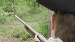Revolutionary War soldier aiming musket at line of trees Stock Footage