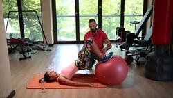 Athletic woman exercising with a fitness ball next to her personal trainer Stock Footage