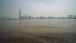 Freight ship sailing on Yangtze river and the cityscape across the river Stock Footage