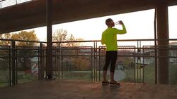 Young man stretching on a fence after jogging / exercising. Stock Footage