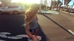 POV happy girl riding skateboard down street at sunset holding selfie camera Stock Footage