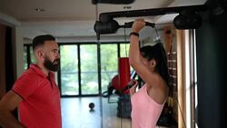 Young woman exercising while being watched by her personal trainer Stock Footage