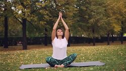 Good-looking girl is putting hands in namaste sitting in lotus position and breating relaxing her body and mind. Meditation, hatha yoga and people concept. Stock Footage