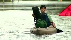 Shot of a man with a guitar paddling in a boat during flooding in Pollocksville, North Carolina Stock Footage