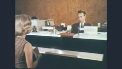1960s: Man shows passbook entries to delighted woman and they exit bank Stock Footage