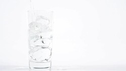 Pouring Pure water into glass with ice cubes on white background Stock Footage