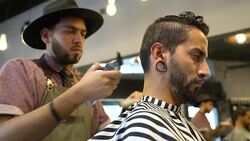 Barber styling customer's hair with electric razor Stock Footage