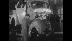 United States, 1930s-1940s: Workers in a factory finalize construction on an automobile moving down a floor track Stock Footage