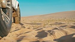 closeup of the legs of a young woman next to a 4x4 car vehicle enjoying the sunset on one of the desert sand dune Stock Footage