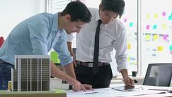 Architects male and Businessman are paper blueprint and building model. Business man suggest idea to designer at modern office. concept of construction, architecture, development and creative. Stock Footage