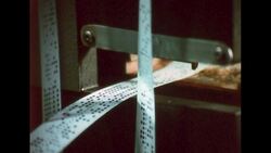 UNITED STATES 1960s: Zoom in, paper punch tape coming out of machine. Stock Footage