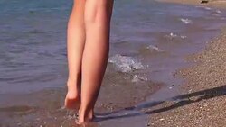 Legs of a girl entering the sea along a sandy beach Stock Footage