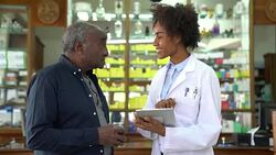 Chemist showing prescription on tablet PC to man Stock Footage