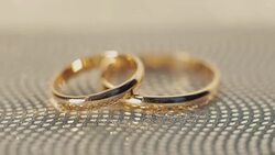 Wedding rings lying on shiny surface shining with light close up macro. Rotate clockwise Stock Footage