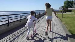 Two little girls Riding Kick Scooter Outdoors. Stock Footage