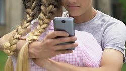 Boy texting on smartphone while embracing girlfriend, lie and betrayal, closeup Stock Footage