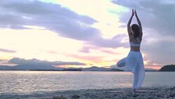 Happy young woman standing yoga pose on the beach at sunset, Sunrise background. Fitness, sport, yoga and healthy lifestyle concept. Stock Footage