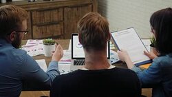Analysts at desk work at laptop showing statistics, looking at graphs and charts Stock Footage