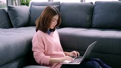 Beautiful young smiling asian woman working on laptop while enjoying drinking coffee in living room at home. Happy female buying online shopping at home. Lifestyle woman at home concept. Stock Footage
