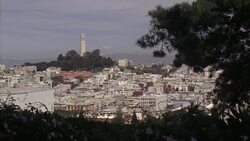 MEDIUM ANGLE OF COIT TOWER FROM A DISTANCE. SEE MULTI-STORY BUILDINGS SURROUNDING COIT TOWER. Stock Footage
