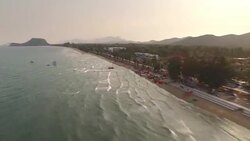 Aerial hyperlapse of a sandy beach from above with kiteboarders riding on the stunning blue water in Pranburi, Thailand Stock Footage
