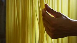 in the morning a young boy touches the hand of a fresh pasta to dry put them to ensure a high quality Stock Footage