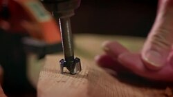 A large drill bit is used to make a hole in a piece of wood in a workshop. Stock Footage