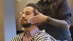 Hairdresser applying aftershave to male customer Stock Footage